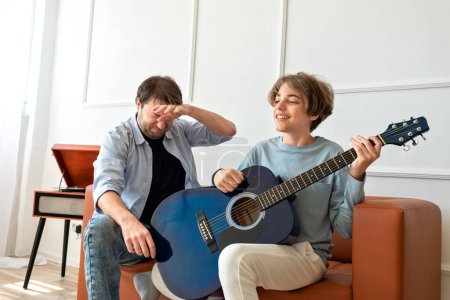 Téléchargez les photos : Père célibataire écoutant son fils jouer de la musique sur un guital acoustique, soutien parental adolescent enfant - en image libre de droit