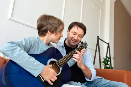 Foto de Hijo adolescente aprendiendo a tocar una guitarra acústica con el apoyo del padre. Felices relaciones familiares de padres solteros, padre amoroso enseñando hijo - Imagen libre de derechos