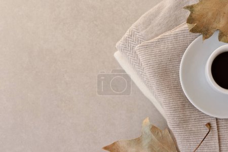 Foto de Fondo de otoño minimalista estético, taza de café caliente, suéteres de punto acogedor, hojas secas sobre un fondo pastel beige neutro, disposición plana, espacio de copia - Imagen libre de derechos
