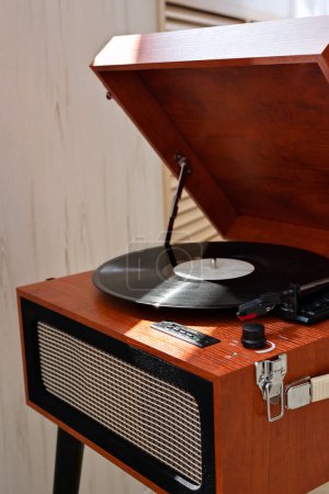 Téléchargez les photos : Esthétique brun bois rétro numérique lecteur vinyle, tourne-disque avec un disque vinyle à la lumière du soleil avec de la poussière, la musique nostalgique tendance moderne. Mur beige neutre, intérieur de la maison - en image libre de droit