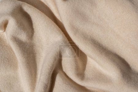 Téléchargez les photos : Doux tissu jersey de laine tricoté fond. Texture tricotée beige neutre froissée désordonnée avec lumière du soleil et ombre. Modèle de marque d'affaires de vêtements d'hiver d'automne esthétique, toile de fond avec espace de copie - en image libre de droit