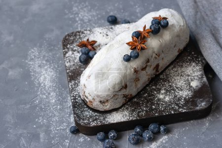 Photo for Christstollen, traditional Christmas holiday treat, German stollen, fruit cake baked with raisins, decorated with a blueberry, anise, sugar powder, delicious sweet authentic homemade bakery - Royalty Free Image