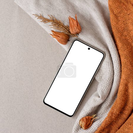 Photo for Blank mobile phone mock up, dried orange flowers on neutral beige and knitted orange background. Aesthetic autumn business brand template - Royalty Free Image