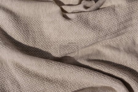 Foto de Desordenado arrugado neutro marrón claro o taupe textura del suéter de punto con luz solar y sombra. Suave tejido de punto de punto de punto de lana fondo. - Imagen libre de derechos