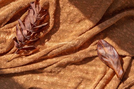 Foto de Hojas de otoño secas marrón desordenado en naranja, fondo de tela de punto de terracota, fondo neutro estilo de vida rústico otoño, espacio de copia. - Imagen libre de derechos