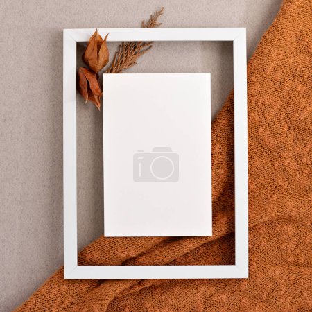 Photo for Blank paper card mock up in frame border with dried flowers on orange knitted cloth and neutral beige background with copy space. Autumn aesthetic square social media brand design template - Royalty Free Image