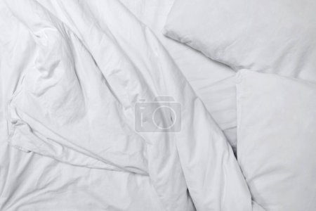 Téléchargez les photos : Couverture en coton froissé blanc, oreillers et drap, chambre à coucher style de vie désordonné. Identité de marque neutre esthétique ou modèle de conception de blog, espace de copie. - en image libre de droit