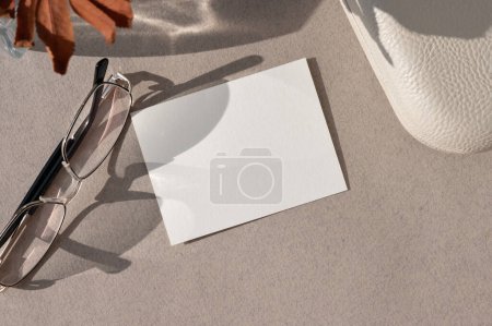 Photo for Minimal autumn business template for branding identity. Blank paper card mockup, eyeglasses, fall brown leaf on neutral beige background, flat lay. - Royalty Free Image