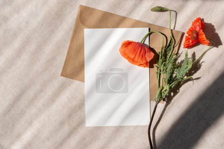 Téléchargez les photos : Modèle de carte vierge, enveloppe et fleurs de pavot rouge sur fond de lin beige avec ombres de soleil style de vie. Jour du Souvenir, Jour de l'Armistice, Modèle de jour du Souvenir. - en image libre de droit