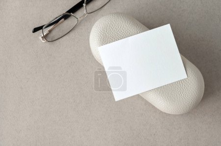 Photo for Blank paper business card mockup with copy space, eyeglasses and case on neutral beige background. Aesthetic minimal template for business branding identity. - Royalty Free Image
