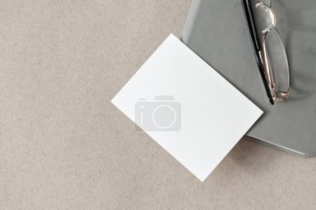 Photo for Minimal business brand template, blank paper card mockup on gray notepad and eyeglasses on neutral beige table background - Royalty Free Image