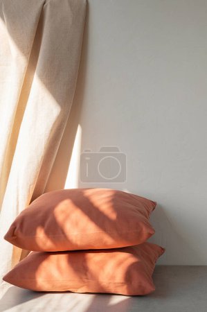 Photo for Warm and cozy home room interior concept, orange pillows on floor, neutral beige linen curtain and empty wall background with natural sunlight shadows pattern. - Royalty Free Image