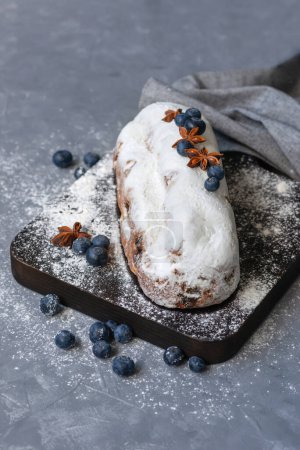 Téléchargez les photos : Dessert traditionnel d'hiver allemand, enflé de raisins secs, de myrtilles et de sucre en poudre, délicieux pain de fruits de Noël sucré sur une planche en bois - en image libre de droit