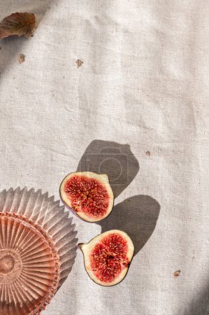 Photo for Aesthetic autumn neutral background, cut fig fruit on neutral beige linen cloth background with natural sunlight shadows. Minimal sustainable brand template, healthy diet fruit concept. - Royalty Free Image