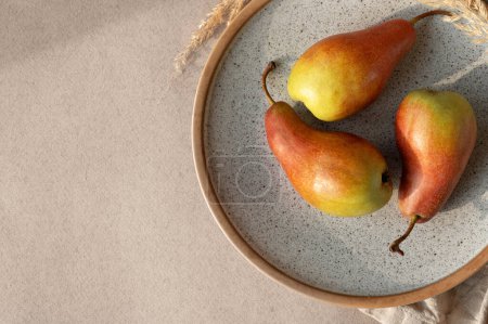 Photo for Red pears on plate on beige table background. Autumn fruits, lifestyle - Royalty Free Image