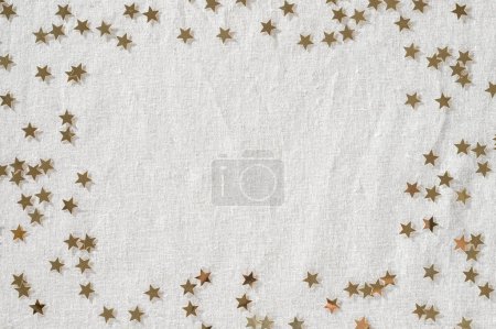 Téléchargez les photos : Confettis étoile dorée sur toile de lin beige neutre. Modèle de conception minimaliste esthétique Nouvel An ou célébration d'anniversaire avec espace de copie. - en image libre de droit