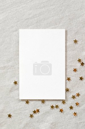 Foto de Plantilla de marca de negocios festiva minimalista para el anuncio de vacaciones de Año Nuevo o folleto publicitario. Tarjeta de papel en blanco maqueta, confeti estrella de oro sobre fondo de textura de lino beige neutro. - Imagen libre de derechos