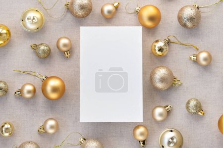 Téléchargez les photos : Modélisation de carte de papier vierge, boules de décoration d'arbre de Noël pastel or, motif ornements sur fond de lin beige neutre. Marque d'affaires festive esthétique, modèle de blog de médias sociaux. - en image libre de droit