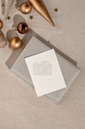 Téléchargez les photos : Modélisation de carte papier vierge, carnet gris étincelant, ornements de Noël en bronze sur fond de nappe en lin beige. Concept de plans et objectifs du Nouvel An, modèle de marque minimaliste esthétique. - en image libre de droit