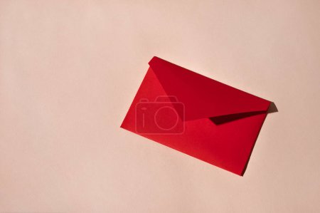 Photo for Minimal love letter concept. Red paper envelope on light pink background with harsh shadows. Holiday greeting postcard or invitation, for birthday, Valentine day. Luxury business branding stationery. - Royalty Free Image