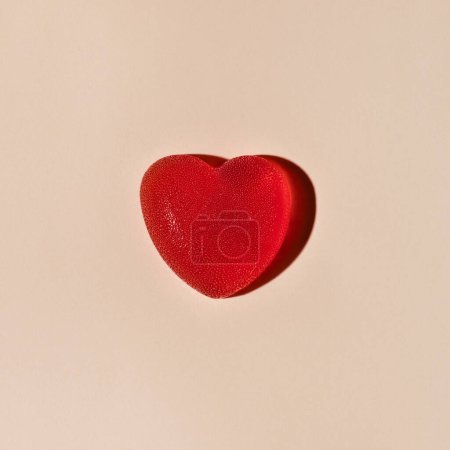 Foto de Dulce caramelo en forma de corazón rojo gelatina sobre fondo beige neutro con duras sombras de luz solar. Concepto de amor mínimo, diseño de tarjetas de felicitación de San Valentín. - Imagen libre de derechos