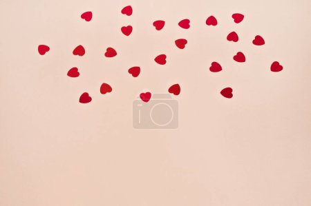 Téléchargez les photos : Motif abstrait avec petits cœurs de confettis rouges sur fond de papier rose pastel. Modèle de conception de carte de voeux primitive simple Saint-Valentin avec espace de copie. - en image libre de droit