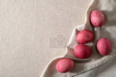 Photo for Pink colored Easter eggs on neutral beige linen tablecloth and napkin background with soft natural sun light and shadow, top view, flat lay, empty copy space. - Royalty Free Image