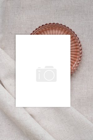 Foto de Tarjeta de papel blanco en blanco maqueta y placa decorativa de color cobre en la superficie de tela de lino beige neutro texturizado. - Imagen libre de derechos