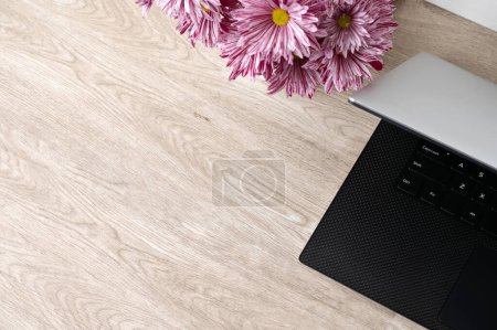 Photo for Empty wooden table, laptop, pink daisy flowers, minimalist lifestyle feminine business branding background, empty copy space, top view. - Royalty Free Image