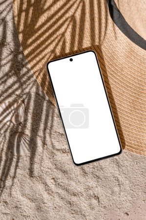 Photo for Aesthetic tropical summer business branding template, mobile phone empty screen mockup, straw hat on sand beach texture background with natural palm tree foliage sunlight shadow. - Royalty Free Image