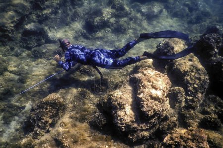 Spearfisher Swims on the Rocky Seabed, Spearfishin