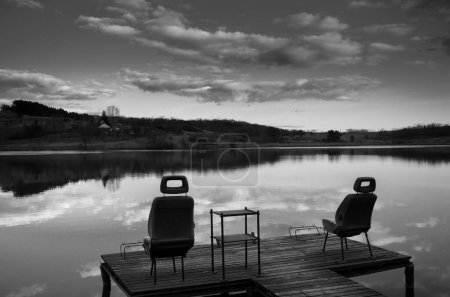 Photo for Black and white photo of lake and pier with fishing place and chairs - Royalty Free Image