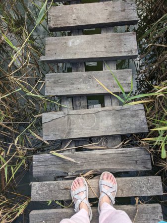 Téléchargez les photos : Femme pieds debout sur le pont en bois sur la rivière - en image libre de droit