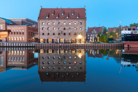 Photo for Buildings reflect in the water at Motlawa river at dusk in Gdansk Poland - Royalty Free Image