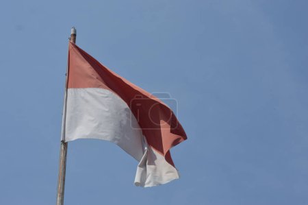 The red and white flag flutters in the sky