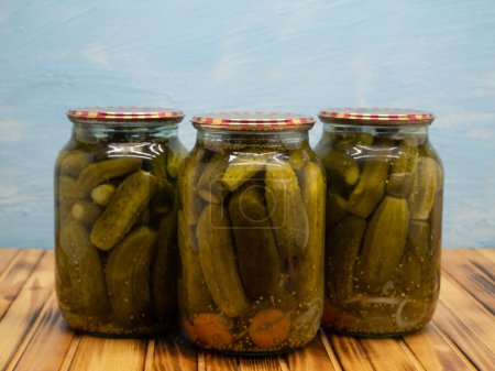 Preservations, conservation. Salted, pickled cucumbers in a jars on an wooden table. Pickling cucumbers at home. Vegetable harvest conservation. Close up.