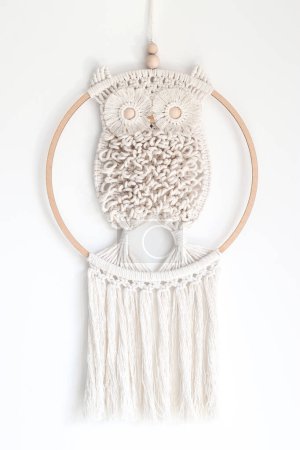 Hand woven white macrame owl in ring hanging on wall