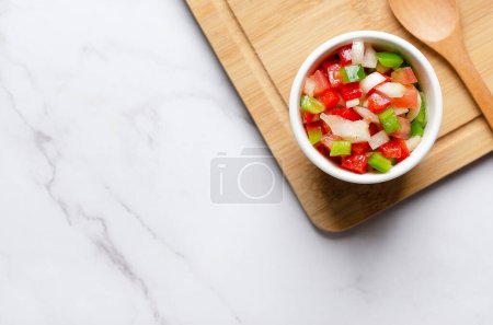 Téléchargez les photos : Sauce Criolla argentine dans un bol sur une planche en bois et fond de marbre blanc avec espace de copie. Vue du dessus. - en image libre de droit