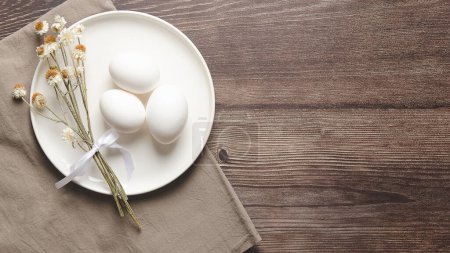 Téléchargez les photos : Table de Pâques avec œufs blancs et fleurs séchées sur fond en bois. - en image libre de droit