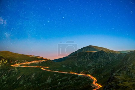 Transalpina road under a starry night with traffic trails along the winding road. Transalpina is one of the highest roads passing the Carpathians in Romania.