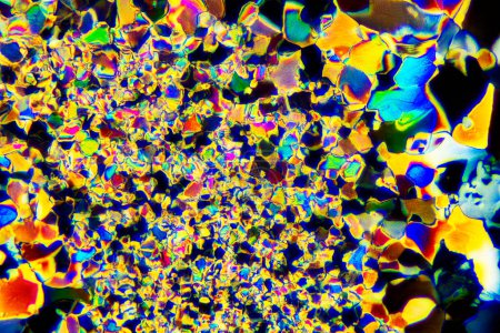 Macro-photographie extrême de cristaux d'acide tartrique formant des motifs d'art moderne abstrait vibrants, lorsqu'ils sont éclairés par la lumière polarisée, sous un objectif de microscope avec un grossissement 50x