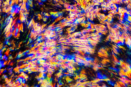 Fotografía macro extrema de cristales de Meloxicam que forman vibrantes patrones abstractos de arte moderno, cuando se iluminan con luz polarizada, bajo un objetivo de microscopio con aumento de 50x