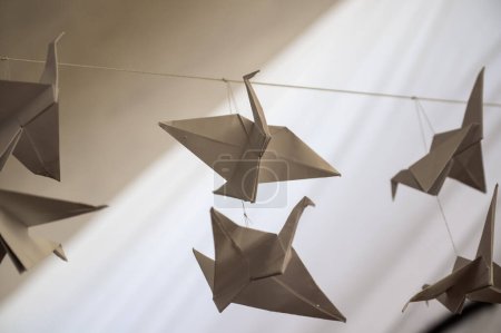 Foto de Japanese folded Origami cranes hanging on with strings. Hundreds handmade paper birds isolated with copy space. 1000 thousand crane tsuru sculpture topic. Symbol of peace, faith, health, wishes, hope - Imagen libre de derechos