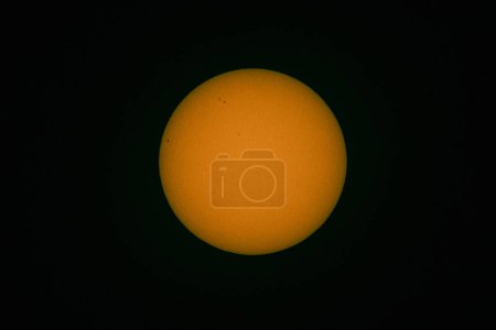 Photo for The solar disk photographed with a telephoto lens. As a result of using an optical filter, a warm color of the sun disc was obtained. Sun spots are visible on the surface. - Royalty Free Image