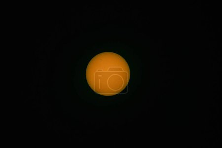Photo for The solar disk photographed with a telephoto lens. As a result of using an optical filter, a warm color of the sun disc was obtained. Sun spots are visible on the surface. - Royalty Free Image