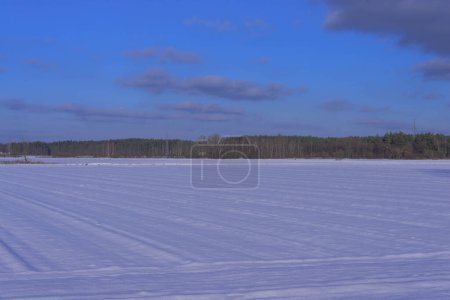 Invierno, día soleado. La llanura, cubierta de tierras de cultivo y prados, está cubierta con una capa de nieve.