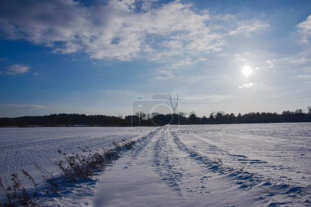 Winter, sunny day. The plain, covered with farmlands and meadows, is covered with a layer of snow.