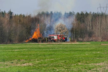 Fire of dry branches collected in agricultural wasteland and extinguishing operation carried out by firefighters. Early spring, the time to burn dry grass.