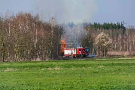 Fire of dry branches collected in agricultural wasteland and extinguishing operation carried out by firefighters. Early spring, the time to burn dry grass.