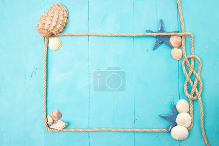 Téléchargez les photos : Jute rope frame with a knot, sea shells, and stars  on blue acrylic wooden boards. - en image libre de droit